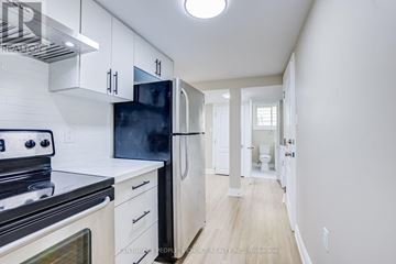 Mississauga (Malton) apartment for rent - A kitchen with white cabinets and a black fridge.