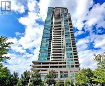 Toronto (Bendale) condo for rent - A tall building with many windows and balconies is surrounded by trees.