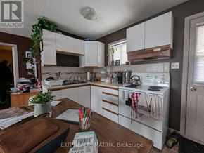 Edwardsburgh/Cardinal multi-family for rent - A kitchen with white cabinets and a wooden table with a plant on it.