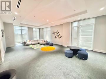 Toronto (Newtonbrook West) condo for rent - A spacious living room with a grey carpet and a large window.
