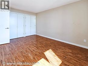 Burnaby apartment for rent - A room with wooden flooring and white walls, featuring a white door and two white closet doors.