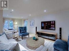 Toronto (St. Andrew-Windfields) apartment for rent - A living room with a white couch, a blue chair, and a television.