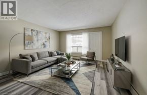 London apartment for rent - A living room with a grey sofa, a glass coffee table, and a television on the wall.