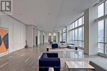 Toronto (Kensington-Chinatown) condo for rent - A spacious living room with a large painting on the wall and a view of the city.
