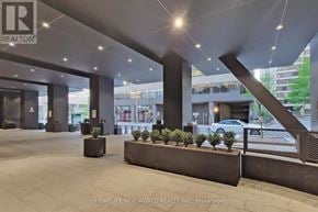 Toronto (Kensington-Chinatown) condo for rent - A large, modern building lobby with a long bench and a row of planters.