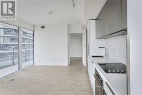 Toronto (Church-Yonge Corridor) condo for rent - A well-lit, empty kitchen with white cabinets and a large window.