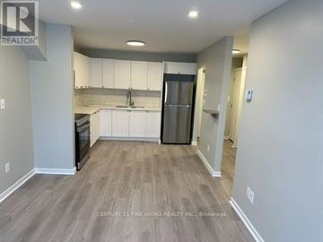 New Tecumseth (Alliston) multi-family for rent - A kitchen with a black refrigerator and white cabinets.