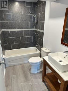 New Tecumseth (Alliston) multi-family for rent - A bathroom with a white toilet, sink, and bathtub.