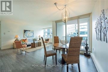 London East (East F) condo for rent - A well-lit living room with a large window and a dining table set with chairs.
