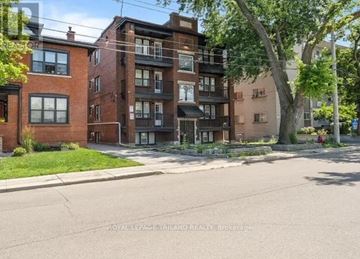Hamilton (Delta) multi-family for rent - A street view of a residential area with brick buildings and a tree in the foreground.