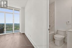 Toronto (Mimico) condo for rent - A white bathroom with a toilet and a window overlooking a cityscape.