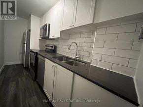 Kitchener multi-family for rent - A kitchen with white cabinets and a black counter top.