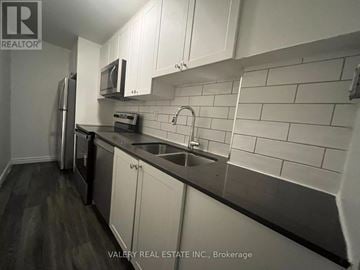 Kitchener multi-family for rent - A kitchen with white cabinets and a black counter top.