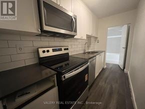 Kitchener multi-family for rent - A kitchen with a stove top oven and microwave above it.