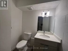 Kitchener multi-family for rent - A bathroom with a toilet, sink, and mirror.