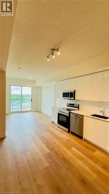 Brantford condo for rent - A kitchen with white cabinets and a wooden floor.