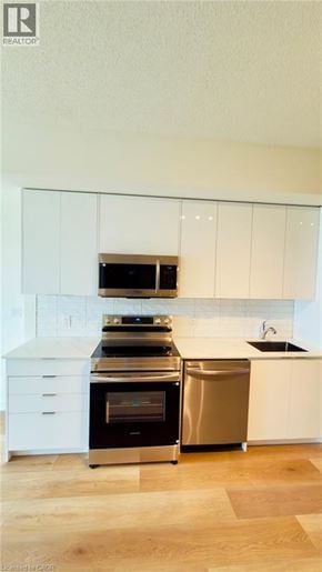 Brantford condo for rent - A modern kitchen with white cabinets and stainless steel appliances.