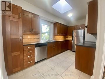 Toronto (Casa Loma) multi-family for rent - A kitchen with brown cabinets and a refrigerator.