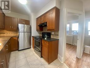 Toronto (Casa Loma) multi-family for rent - A kitchen with wooden cabinets and a stainless steel refrigerator.