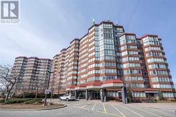 Toronto (Rouge) condo for rent - A large, modern building with a red and white entrance and a car parked in front.