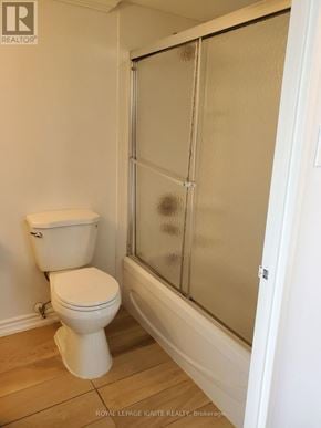 Toronto (Rouge) condo for rent - A white toilet in a small bathroom with a glass shower door.