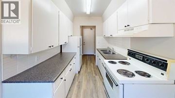 Grande Prairie apartment for rent - A white kitchen with a stove top oven and cabinets.