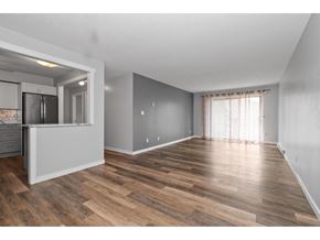 Chilliwack apartment for rent - A spacious room with wooden flooring and a kitchen area to the left.
