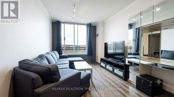 Toronto (St. Andrew-Windfields) condo for rent - A living room with a grey couch and a television.