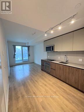 Toronto (South Riverdale) condo for rent - A kitchen with wooden floors and a microwave above the stove.