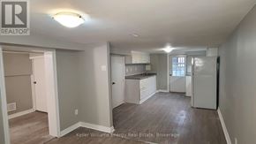 Oshawa (Central) apartment for rent - A well-lit, spacious kitchen and living room area with a refrigerator, sink, and cabinets.