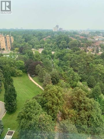 Mississauga (Cooksville) condo for rent - A lush green park with a winding path and apartment buildings in the distance.
