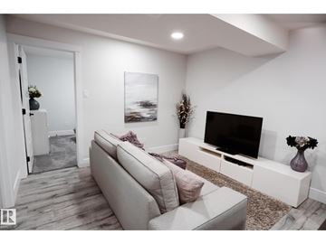 Edmonton apartment for rent - A modern living room with a grey sofa and a black television.