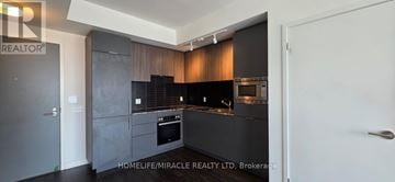 Toronto (Banbury-Don Mills) condo for rent - A modern kitchen with dark wood cabinets and a white door.