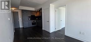 Toronto (Banbury-Don Mills) condo for rent - A spacious kitchen with dark wood floors and white walls.