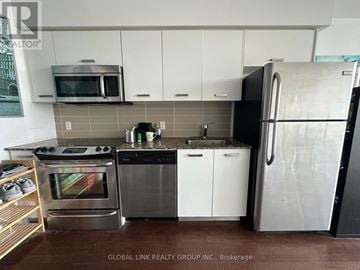 Toronto (Bay Street Corridor) condo for rent - A kitchen with a stainless steel refrigerator, microwave, oven, and dishwasher.