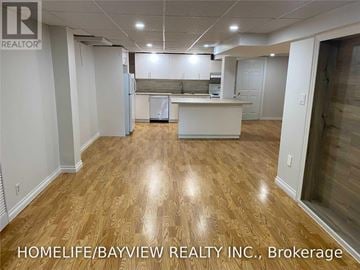 Richmond Hill (South Richvale) apartment for rent - A real estate company is showcasing an empty, well-lit kitchen and living room with hardwood floors.