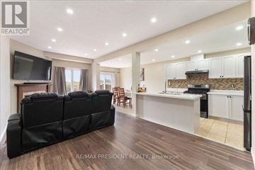 Hamilton (Binbrook) townhouse for rent - A modern living room with a black sofa and a kitchen area in the background.