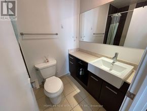 Toronto (Bay Street Corridor) condo for rent - A white toilet is in a small bathroom with a sink and a mirror.