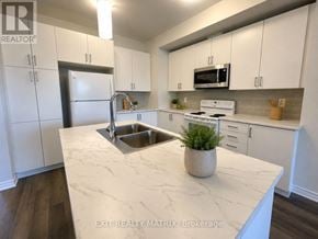 Russell townhouse for rent - A kitchen with white cabinets and a marble countertop.