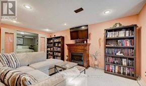 Pickering (Amberlea) apartment for rent - A living room with a grey couch, a fireplace, and a bookshelf filled with books.