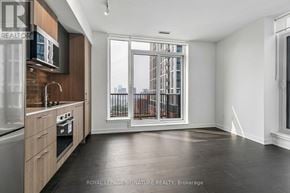 Toronto (Regent Park) condo for rent - A spacious kitchen with dark floors and a view of the city through the window.