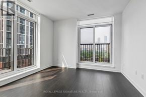Toronto (Regent Park) condo for rent - A room with a large window and a balcony overlooking a cityscape.