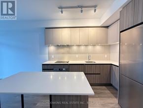 Vaughan (Beverley Glen) condo for rent - A modern kitchen with a white table and wooden cabinets.