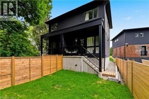 Brantford apartment for rent - A modern black house with a wooden fence and green lawn.