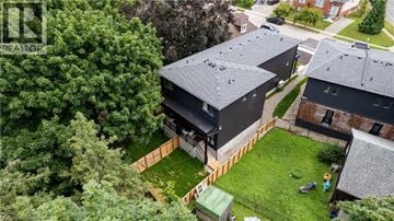 Brantford apartment for rent - A modern house with a black roof is surrounded by a green lawn and trees.