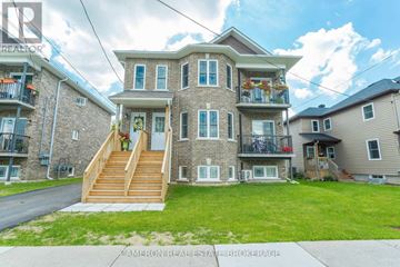 Cornwall triplex for rent - A large house with a balcony and a staircase leading to the front door.