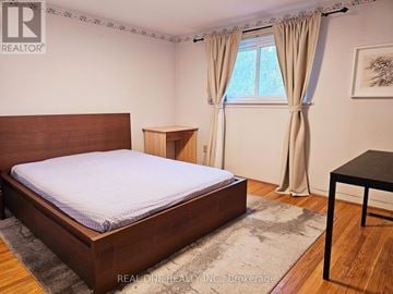 Toronto (Hillcrest Village) townhouse for rent - A bedroom with a large bed and a small table.