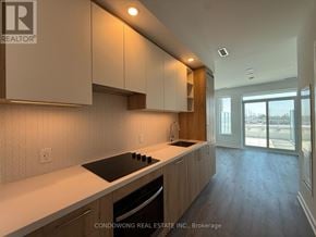 Vaughan (Vaughan Corporate Centre) condo for rent - A modern kitchen with wooden cabinets and a black countertop.