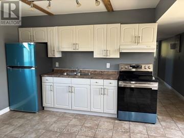 St. Catharines (Burleigh Hill) triplex for rent - A kitchen with a blue refrigerator, white cabinets, and a black stove top oven.