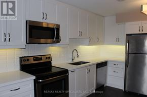 Mississauga (Port Credit) multi-family for rent - A kitchen with white cabinets and a black stove top oven.